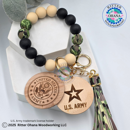 silicone beaded in tan, black and green camo  bracelet/ wristlets  with a tassel in camo design and round wooden disk with military logo engraded