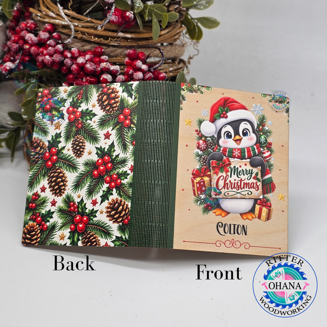 Personalized wooden Christmas gift card holders featuring penguin designs with custom names and festive holiday artwork on the back of holly and pine tree braches