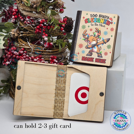 Personalized wooden Christmas gift card holder for kids featuring a colorful dabbing reindeer, Too Busy Sleighin' to Be Nice saying, custom name, and reusable magnetic wooden money holder.