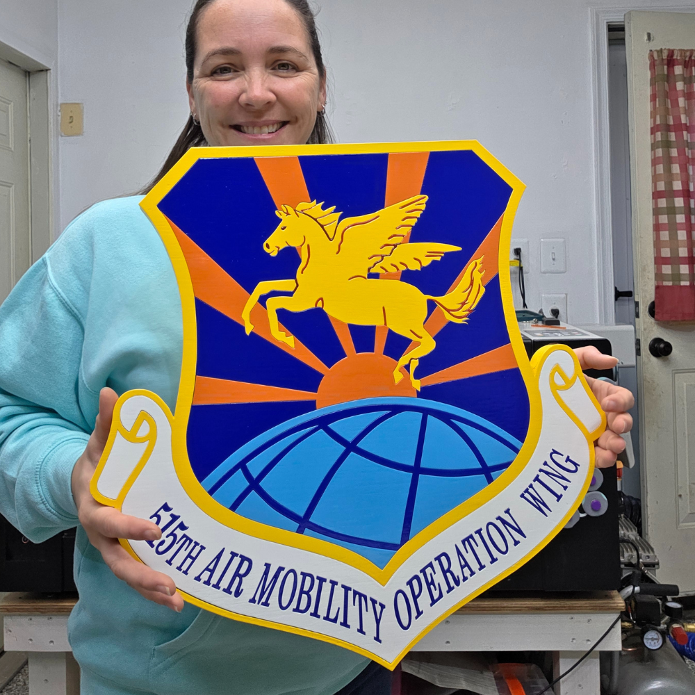 Person holding a large emblem with a winged horse design in an indoor setting