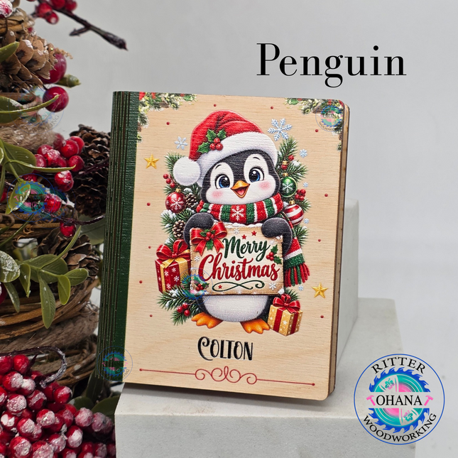 Personalized wooden Christmas gift card holders featuring penguin designs with custom names and festive holiday artwork.