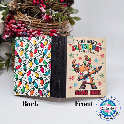 Personalized wooden Christmas gift card holder for kids featuring a colorful dabbing reindeer, Too Busy Sleighin' to Be Nice saying on the front view, custom name, and showing a scattered christmas light design on the back of the gift card holder