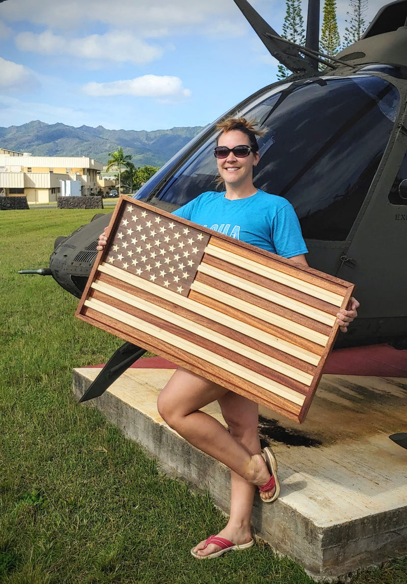 Person holding a wooden American flag in front of a helicopter
